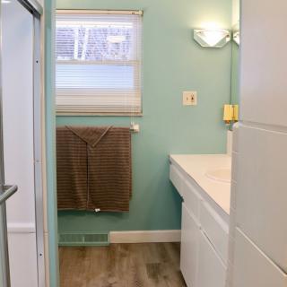 A modern bathroom with mint green walls, a large sink, and a towel hanging by the window.