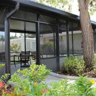 A screened porch with outdoor seating surrounded by a garden.