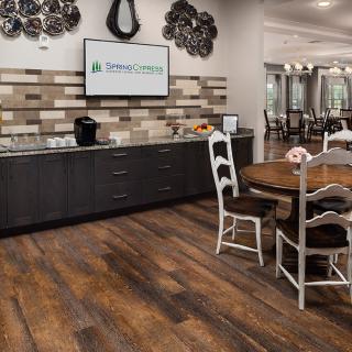 A cozy kitchen area with wooden flooring, a round table with chairs, and modern cabinets along the wall.