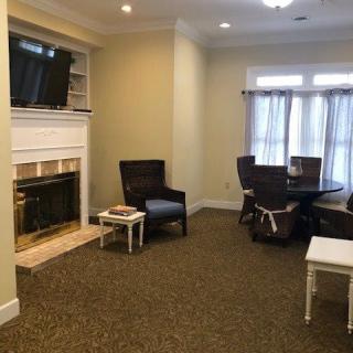 A cozy living room with a fireplace and television, featuring comfortable chairs and a dining table.