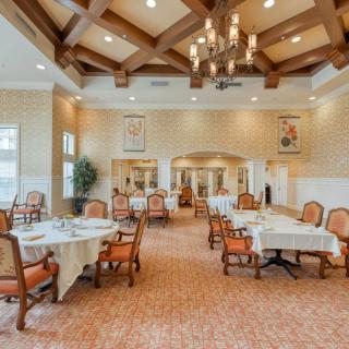 A spacious and elegantly decorated dining room with tables and chairs arranged neatly under a chandelier.