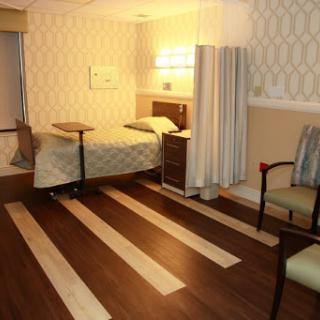 A welcoming hospital room designed for patient comfort, featuring a bed, seating area, and soft lighting.