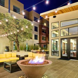 A modern apartment complex patio with a cozy fire pit and string lights.