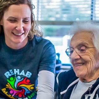 A caregiver and an elderly woman share a joyful moment together.