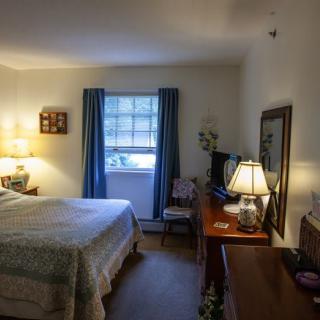 A cozy bedroom with a bed, lamps, and a window adorned with curtains.