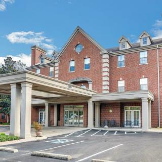 A brick facade hotel building with a covered entrance and parking spaces in front.