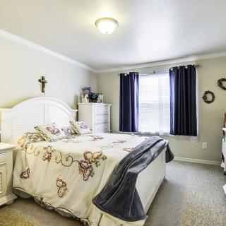 A cozy bedroom with a neatly made bed, decorated with butterfly-themed bedding and surrounded by simple furnishings.
