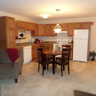 A cozy kitchen and dining area with wooden cabinets, a dining table set, and modern appliances.