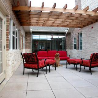 A cozy outdoor patio with red-cushioned furniture under a wooden pergola.