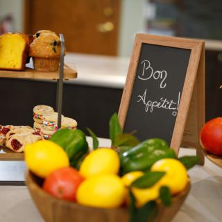 A display of fresh fruits and desserts with a 'Bon Appetit' sign.