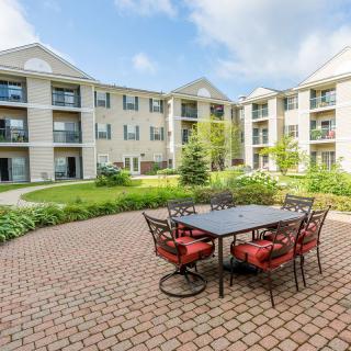 A well-landscaped courtyard with patio furniture in front of a multi-story apartment building.