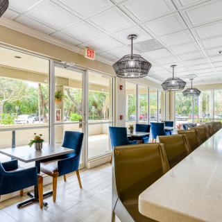 A modern and spacious cafe interior with comfortable seating and large windows.