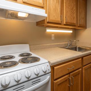 A compact kitchen with wooden cabinets, a stove, and a sink.
