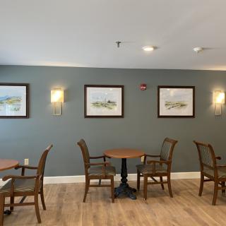 A cozy dining area with tables and chairs, decorated with wall art and warm lighting.