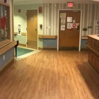 An empty hospital hallway with wooden flooring and a reception area.