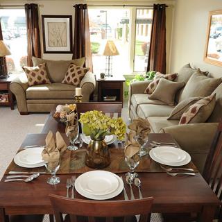 A cozy living room with a dining table set for four, featuring comfortable sofas and warm decor.
