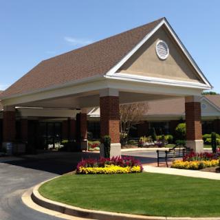 A welcoming entrance of a facility surrounded by vibrant landscaping under clear blue skies.