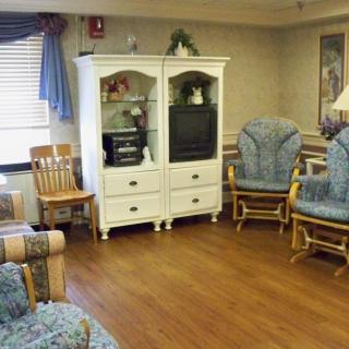 A cozy living room with a white entertainment center, rocking chairs, and wooden flooring.