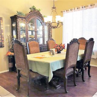A beautifully arranged dining room featuring a large table surrounded by elegant chairs and a decorative chandelier.