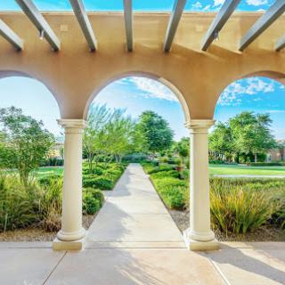 A serene view of a landscaped garden framed by elegant arches under a clear blue sky.