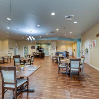 A spacious and well-lit dining area with tables and chairs arranged neatly on a wooden floor.