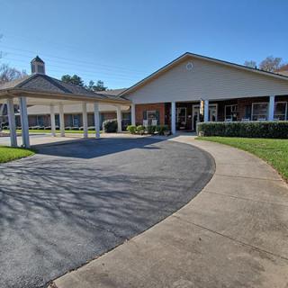 A building with a covered entrance and driveway on a sunny day.