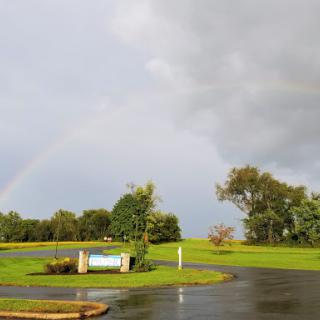 A beautiful rainbow arches across the sky after a refreshing rain shower.