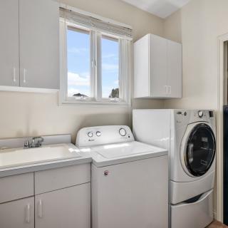 A modern laundry room featuring a washing machine, dryer, and cabinets.