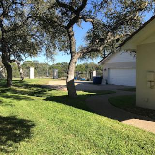 A sunny day in a residential area with lush green grass and trees lining the pathway.