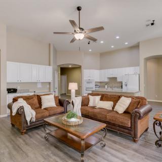 A modern open-concept living room with leather sofas and a view into the kitchen.