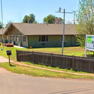 A house with a yard and fence in a residential area, featuring a sign at the corner.