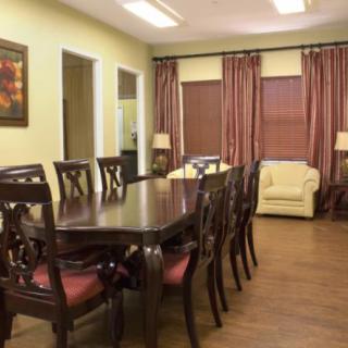 A well-furnished dining room featuring a long wooden table with chairs and elegant curtains.