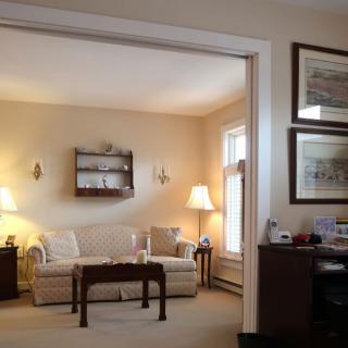 A cozy living room with classical decor, featuring a comfortable sofa, warm lighting from lamps, and framed art on the walls.