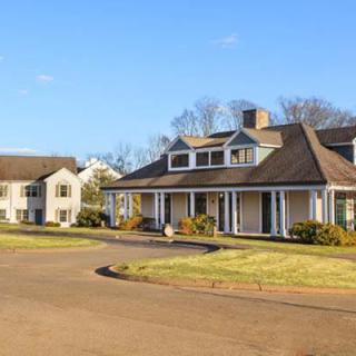 A peaceful suburban neighborhood with traditional-style houses, surrounded by lawns and trees under a clear blue sky.