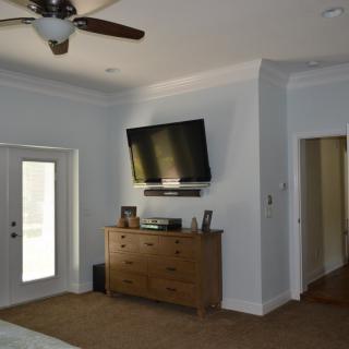 A modern bedroom featuring a wall-mounted television and a wooden dresser.