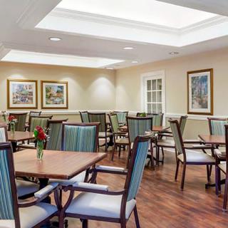 A modern dining room with neatly arranged tables and chairs, highlighted by warm lighting and tasteful artwork.