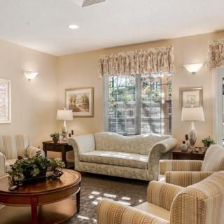 A cozy and well-decorated living room featuring a sofa, armchairs, coffee table, lamps, and artwork.