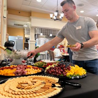 A man serves a colorful array of fruits and snacks at a buffet.