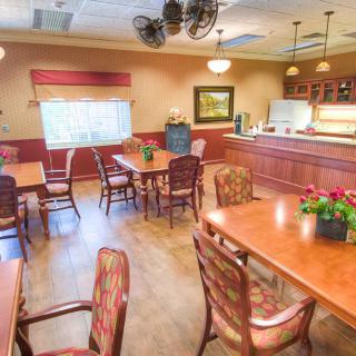 A cozy dining area with wooden tables and chairs, warmly lit with elegant decor.