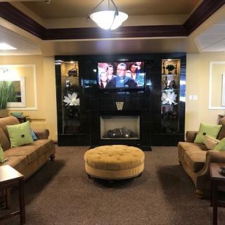 A cozy living room with a central fireplace, TV, and comfortable seating.