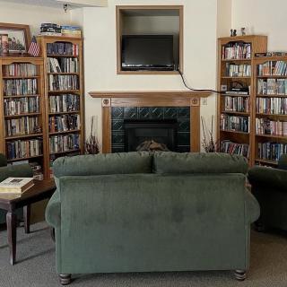A cozy living room library with bookshelves, a sofa, and a fireplace.