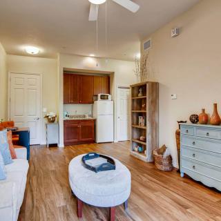 A cozy living room with modern decor featuring wooden flooring, a bookshelf, and a ceiling fan.