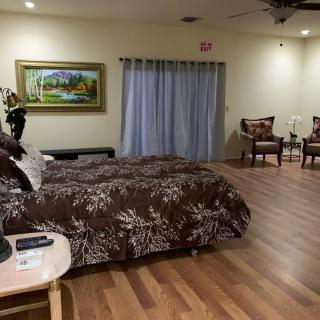 A spacious bedroom with a large bed, elegant decor, and wooden flooring.