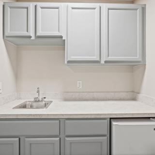A minimalist kitchen setup with light gray cabinets and a small sink.