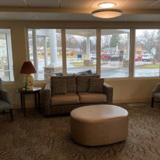 A cozy living room with a sofa, ottoman, and large windows.