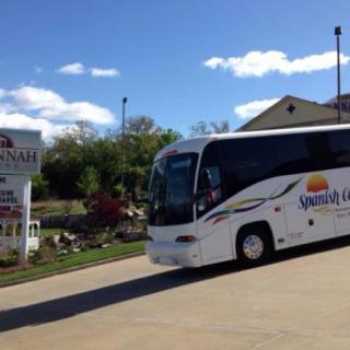A tour bus parked near a sign on a sunny day.