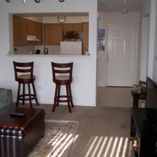 A cozy apartment living room with an open kitchen area and bar stools.