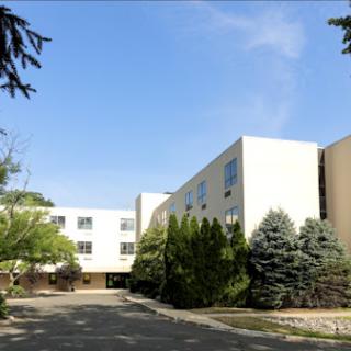 A view of a modern building surrounded by greenery and under a clear blue sky.