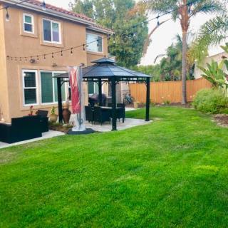 A well-maintained backyard with a lush green lawn, featuring a gazebo and outdoor seating area.