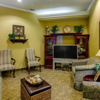 A cozy living room with a television, sofa, chairs, and decorative elements.